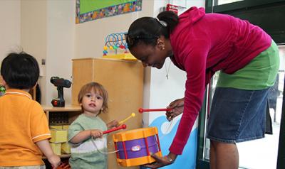 Teacher plays with a young child using a drum