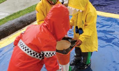 children in raincoats playing outdoors with a traffic cone