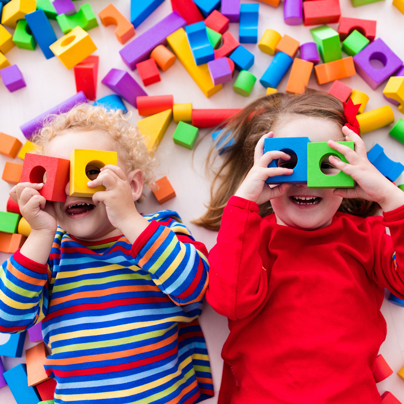 Two toddlers playing in colorful blocks