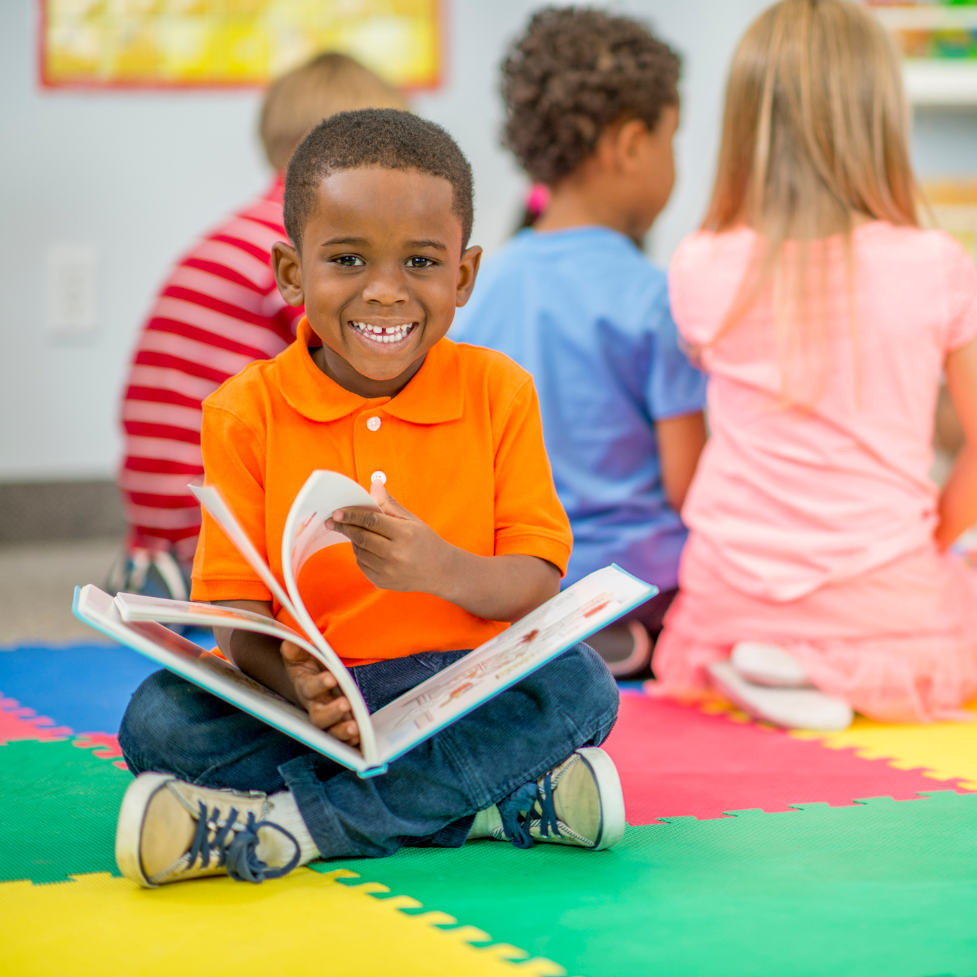 Boy reading a book in preschool class